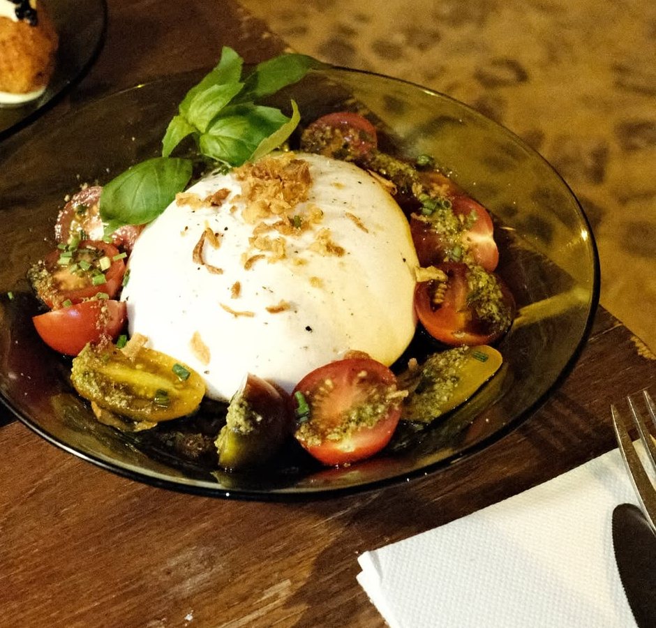 Burrata num prato de vidro com tomate cortado e folhas de manjericão