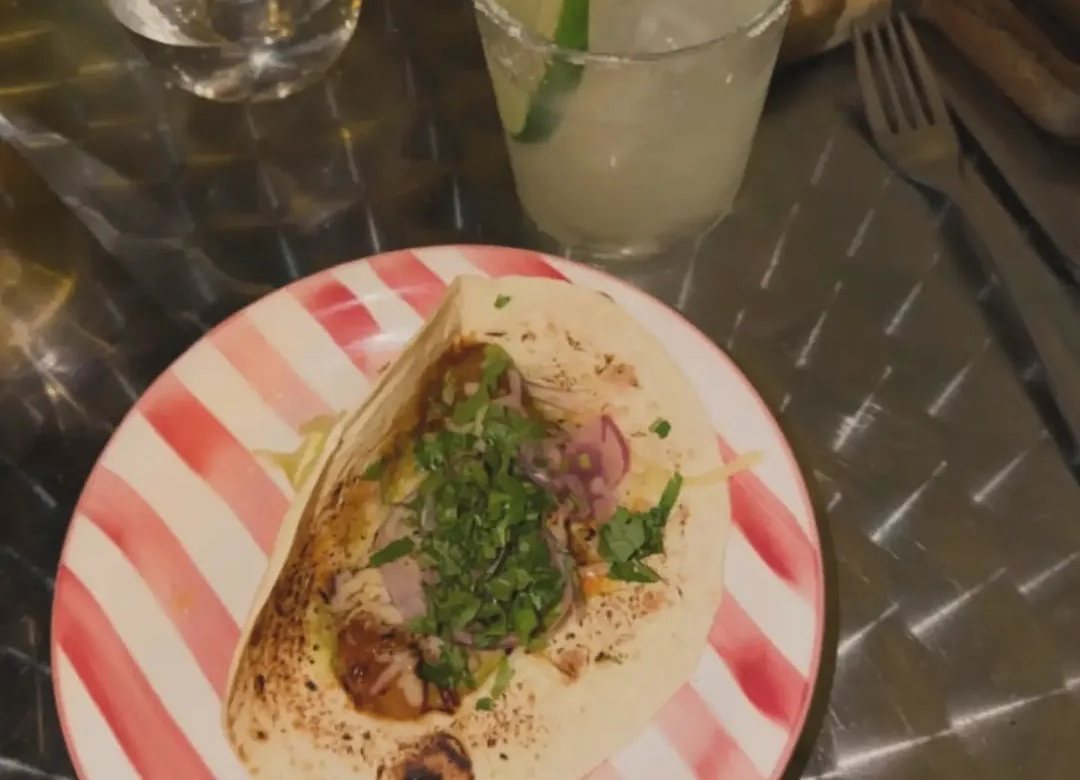 Taco com coentros e cebola roxa num prato às riscas vermelhas